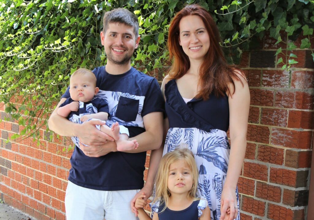 A family consisting of a man, women, toddler daughter, and newborn baby.